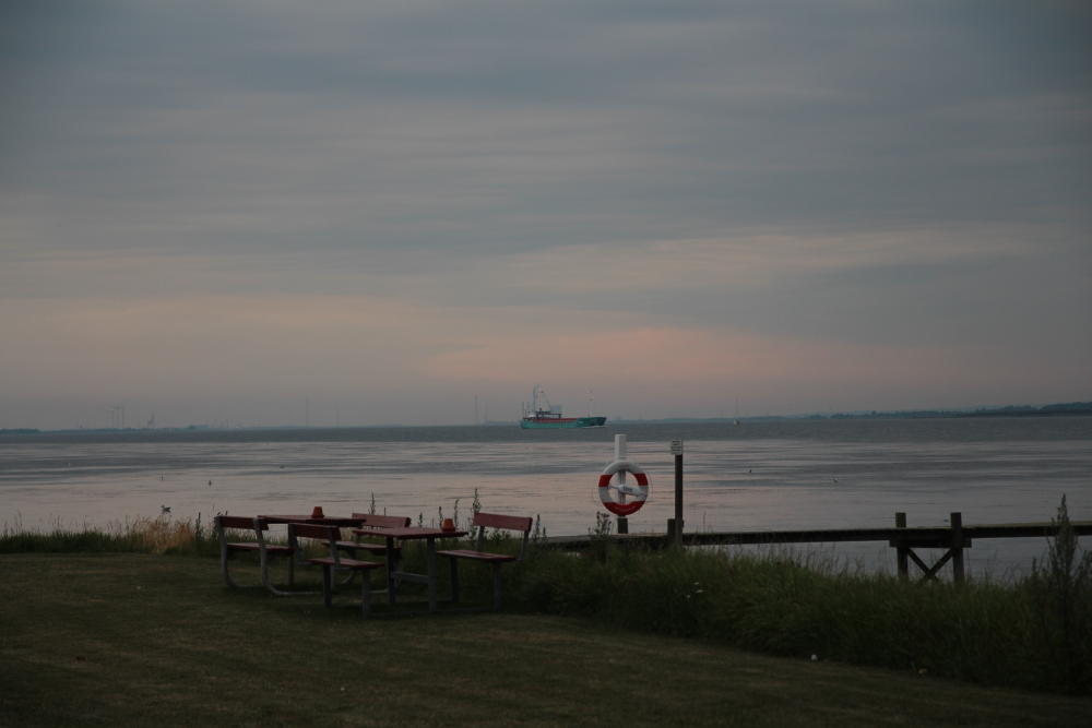 In der Ferne liegt Aalborg und wahrscheinlich von dort kommt im Abendlicht ein Schiff.
